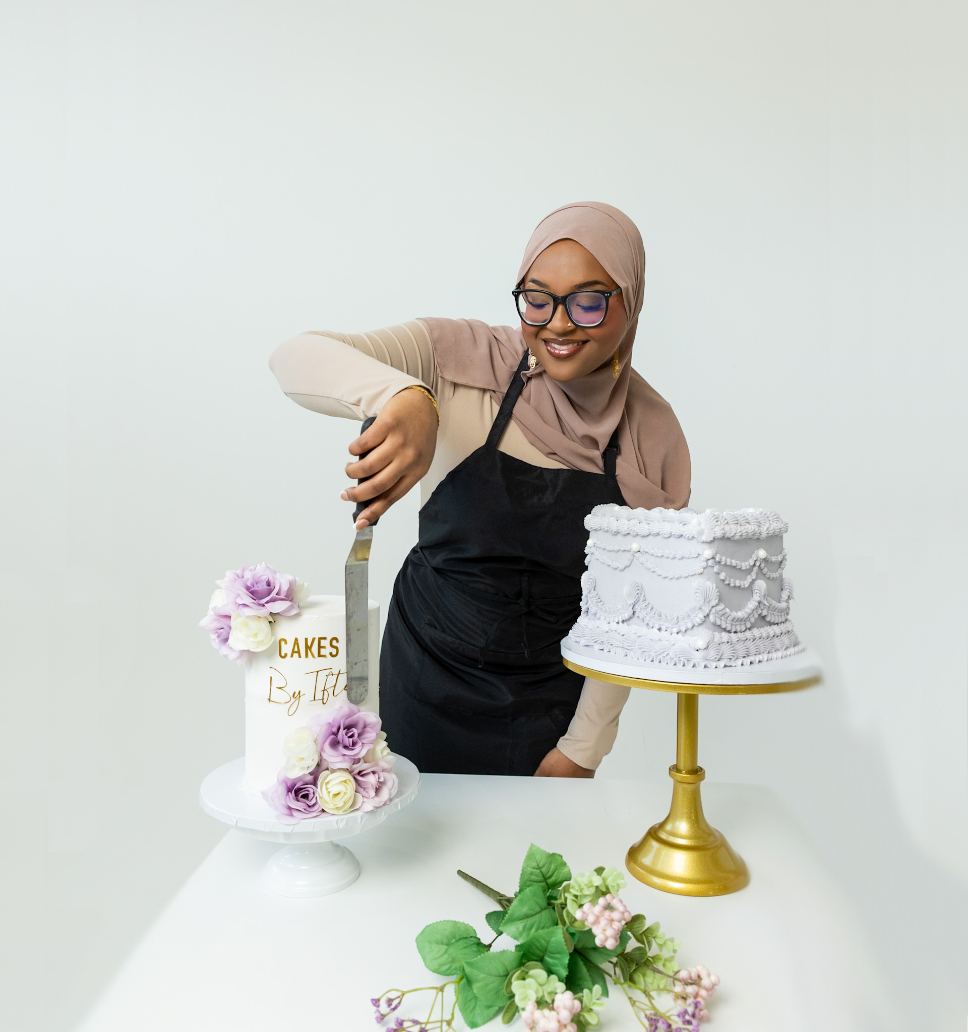 Iftu frosting a cake between two custom celebration cakes